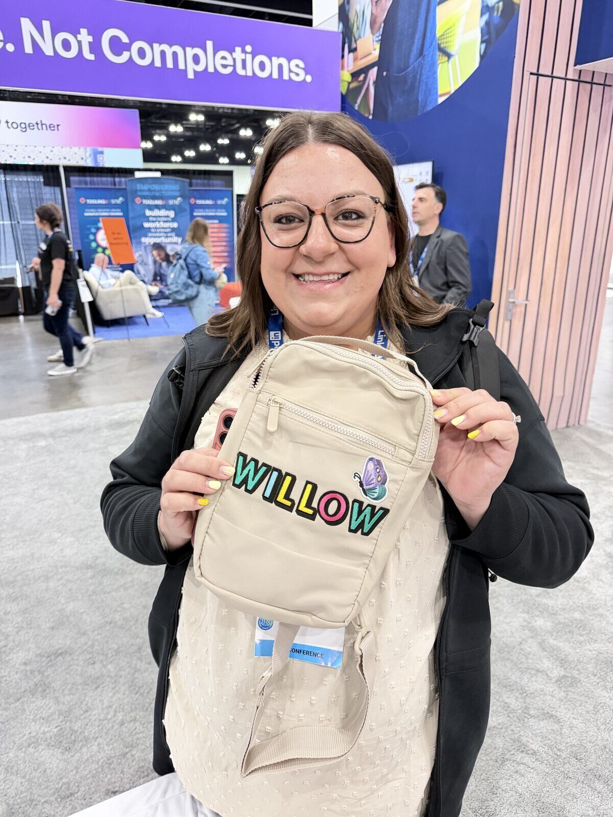 Conference attendee holding a canvas sling bag personalized with her name in colorful lettering